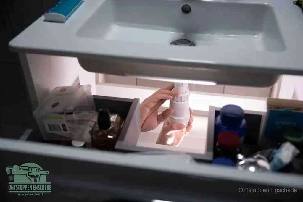 Een pompfles met zeep boven een wastafel, de heet water en afwasmiddel-methode om een vetprop in de afvoer los te maken in Enschede