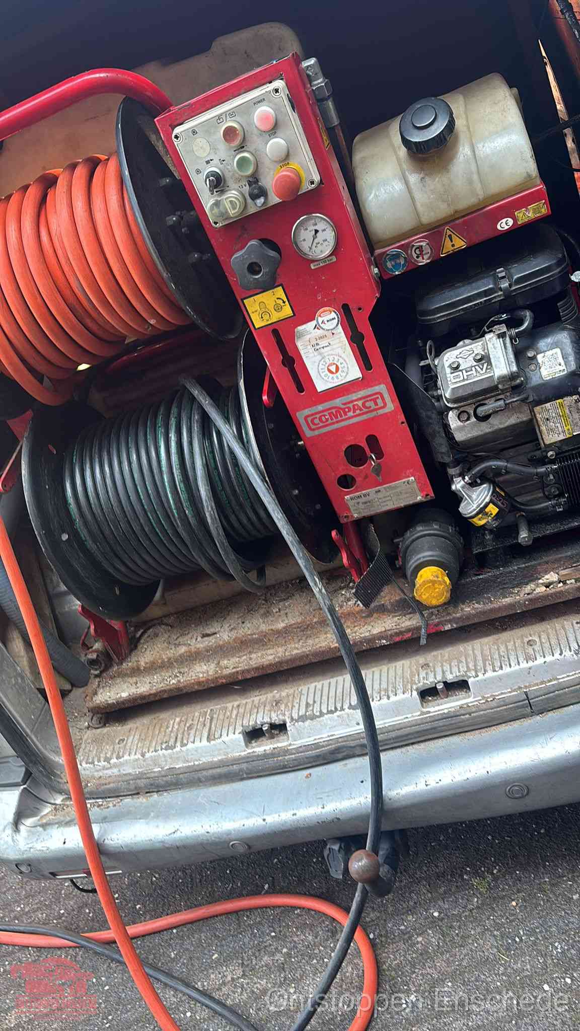 Een rood hogedruk-rioolreinigingstoestel met slangen in de laadbak van de bedrijfsbus, apparatuur voor een hardnekkige wc-verstopping in Enschede