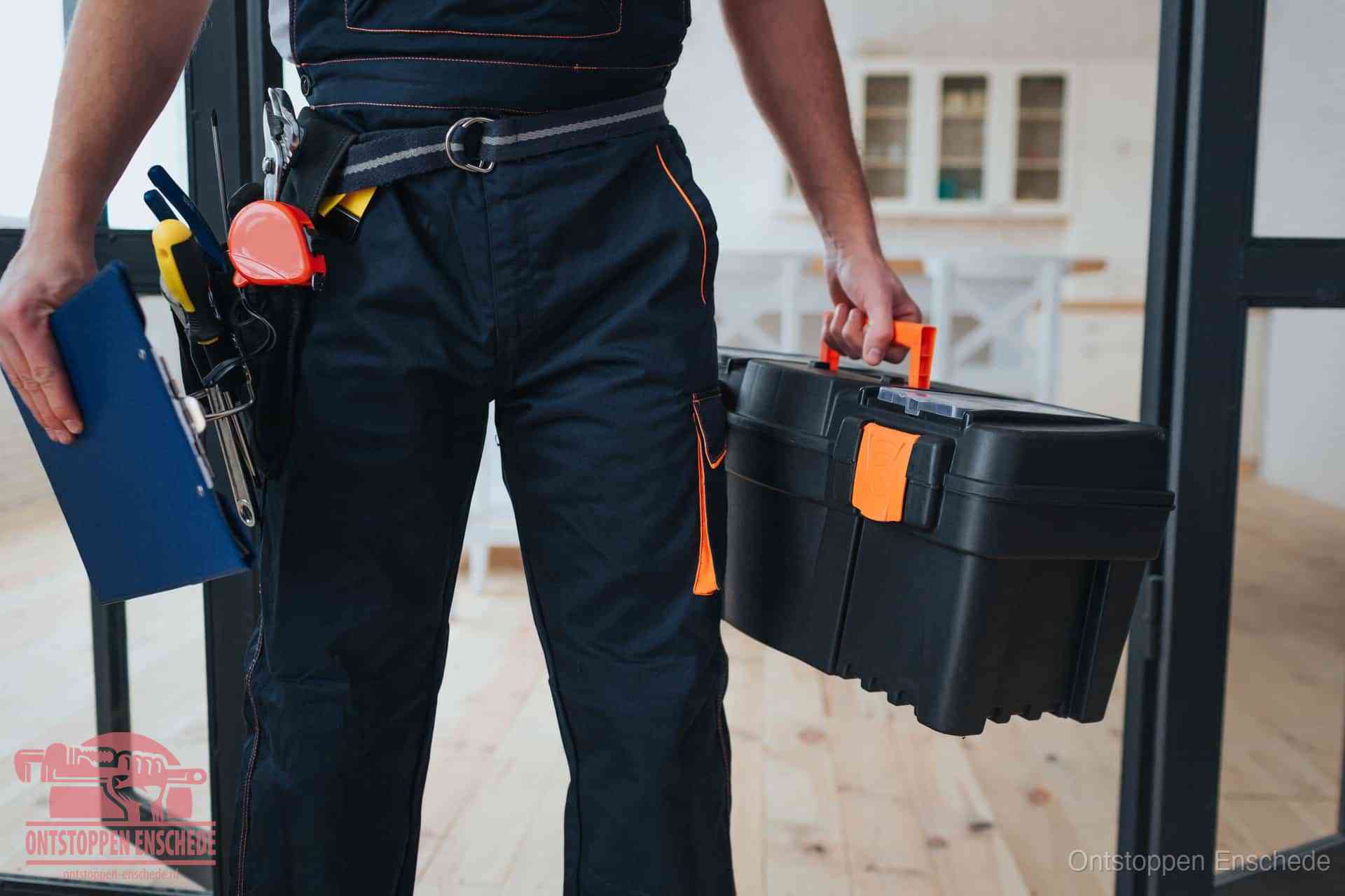 Een monteur met gereedschapsriem en klembord, klaar om een transparante prijs voor het wc ontstoppen in Enschede te geven