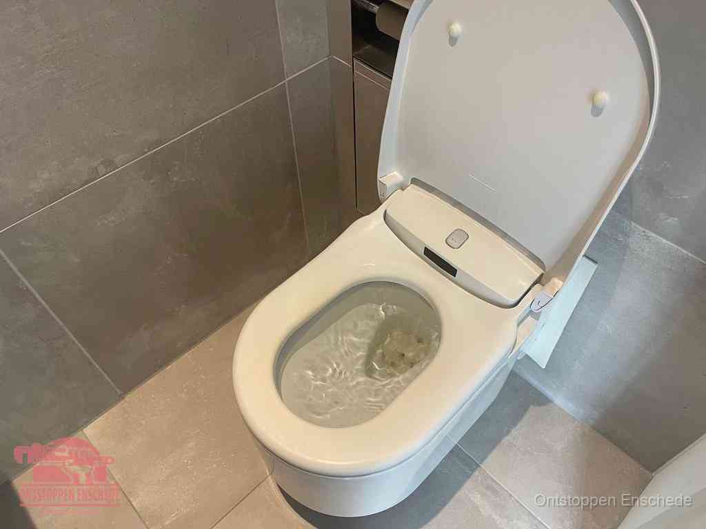Een toiletpot vol troebel water met drijvend papier en restanten, de meest voorkomende oorzaak van een verstopte wc in Enschede