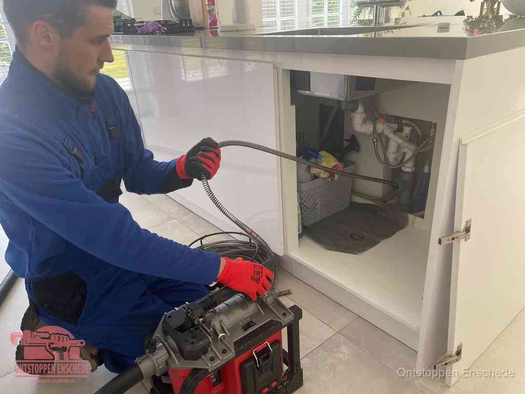 Een monteur reinigt de keukenafvoer grondig met een veermachine om terugkerende gootsteenverstoppingen te voorkomen in Enschede