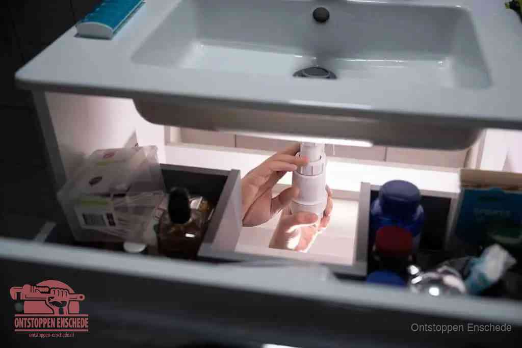 Een pompfles met zeep boven een wastafel in de toiletruimte, de warm water en afwasmiddel-methode om de wc te ontstoppen in Enschede