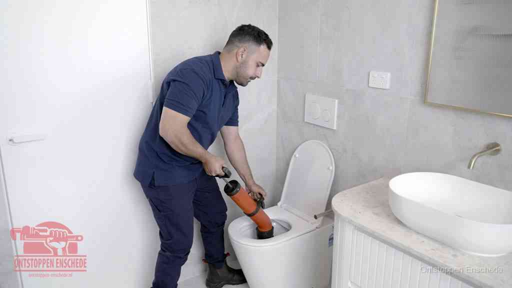 Een monteur gebruikt een handmatige perspomp (toiletontstopper) op een wandcloset tijdens het professioneel wc ontstoppen in Enschede